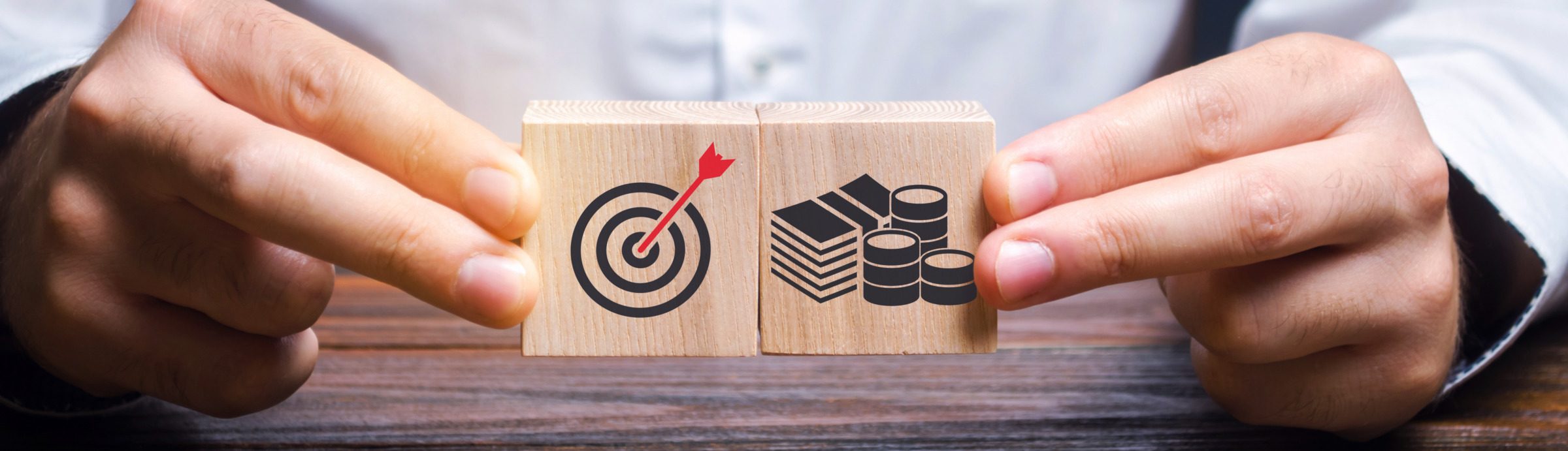 Businessman collects wooden blocks with the image of the goal and money. The concept of doing business and finance. Setting goals and objectives for maximum profit. Strategy and Planning